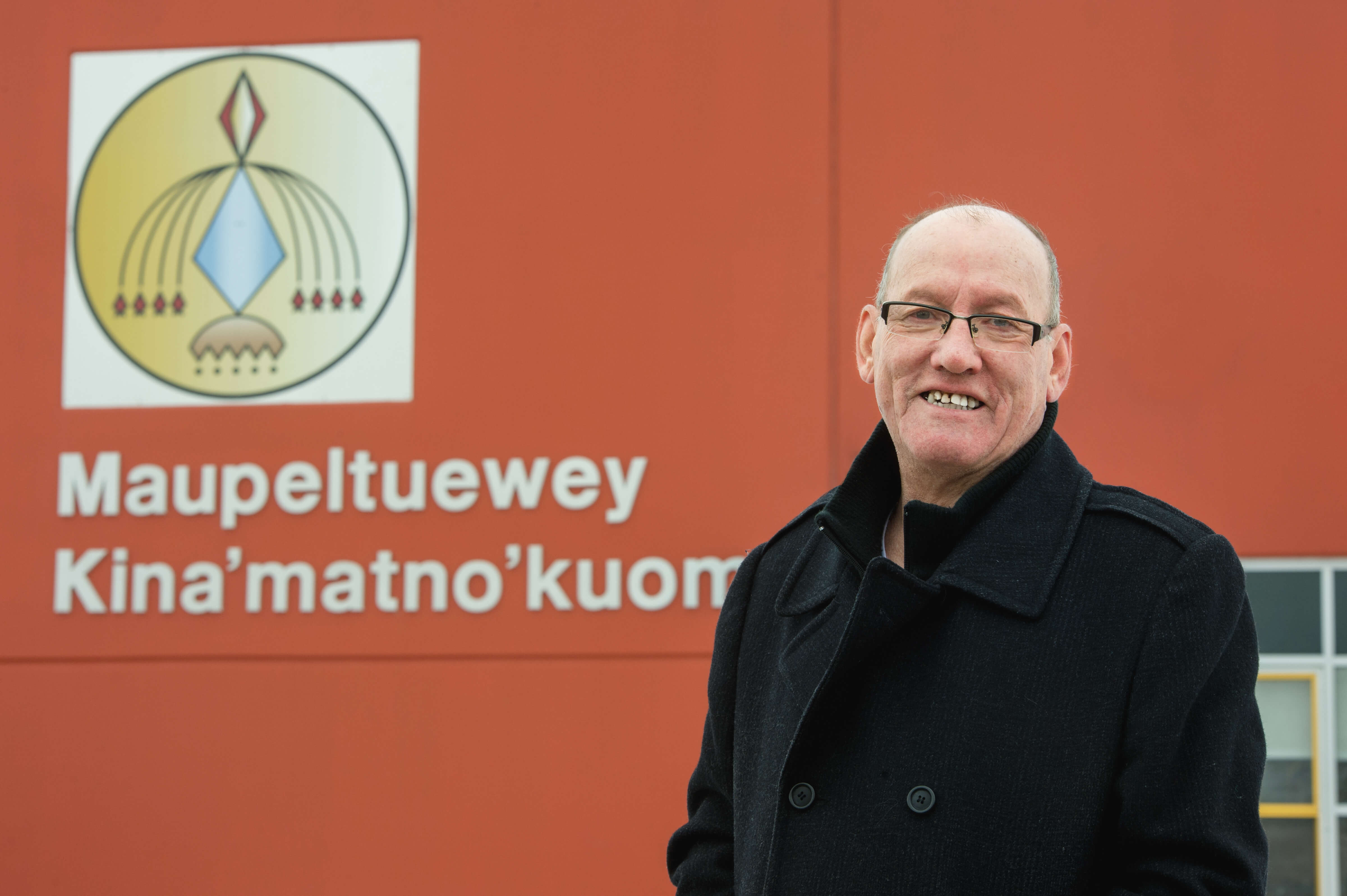Man standing in front of a wall with a First Nation school name
